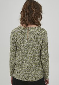 Grøn blomster langærmet bluse med en lille nøglehul detalje i ryggen, tekstureret stof med spredte hvide blomster og en afslappet pasform.