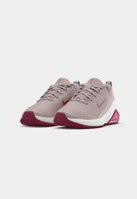 Világos rózsaszín futónadrág, textúrált hálós felsőrésszel, fehér középtalppal és sötét rózsaszín talppal. Az oldalán pink Nike logó található.