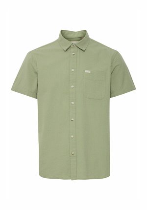 Chemise à manches courtes avec boutons en tissu texturé vert clair. Comprend une poche poitrine et une petite étiquette logo près de la poche.