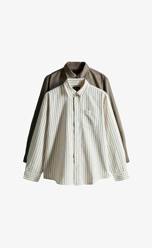 Pitkähihainen nappikauluspaitojen setti, jossa yksi ruskea yksivärinen ja yksi valkoinen, jossa ohuet mustat pystysuorat raidat, molemmissa kaulukset ja kalvosimet.