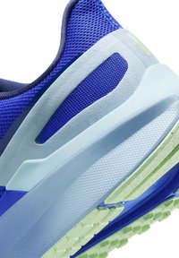 Sezione di scarpe da corsa in mesh blu, con sovrapposizioni testurizzate in azzurro e verde. Presenta una suola imbottita con un battistrada decorato.