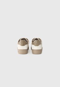 Baskets en suède beige et blanc cassé, avec un bout arrondi, un tirette lisse au talon et une semelle texturée. Logo embossé sur le talon.