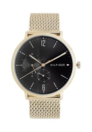 Rund guldfarvet armbåndsur med sort urskive, guldfarvet mesh-rem, tre visere, dato og 24-timers underskiver samt Hilfiger-logo på højre side.