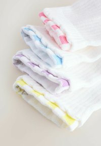 Stapeltje witte sokken met gekleurde accenten in roze, blauw, paars en geel op een lichte ondergrond.