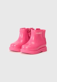 Pink waterproof booties made of shiny rubber, featuring a chunky sole and heel, with a side zipper and elastic accents for easy wear.