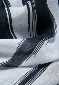 Tissu rayé noir et blanc avec une texture légère et transparente ; présente des lignes irrégulières et fluides sur un fond clair.