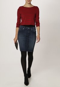 Röd och svart randig långärmad topp kombinerad med en mörk denimpencilkjol och svarta strumpbyxor, kompletterad med svarta klackar och en clutch.