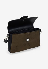 Bolso de mano de cuero negro con un frente de ante verde oliva, cierre de botón de presión plateado y una correa desmontable; bolsillo con cremallera interior visible.
