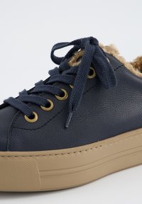 Baskets en cuir marine avec doublure en fausse fourrure, bout rond, œillets dorés et semelle en caoutchouc beige texturée. Coutures doubles pour plus de durabilité.