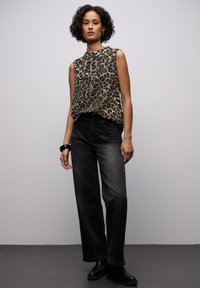 Beżowa i czarna bluzka bez rękawów w panterkę, zestawiona z ciemnoniebieskimi, szerokimi spodniami z wysokim stanem i czarnymi botkami za kostkę.