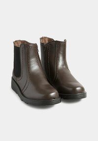 Bruna läderankelboots med elastiska sidopaneler, naturligt foder och texturerade gummisulor. Har en slät finish och sömdetaljer.