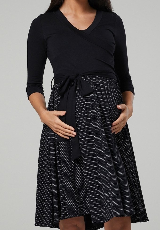 Vestido negro tipo envoltura con mangas tres cuartos, falda de lunares y un lazo en la cintura, hecho de una tela suave y elástica.