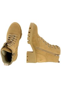 Botines de ante beige con suela de goma, diseño de cordones, cremallera lateral, punta redonda y detalles de costura reforzada.