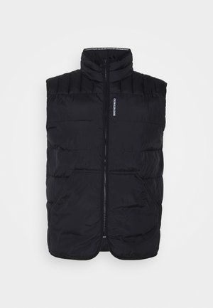 Zwarte mouwloze puffer-vest met hoge kraag, ritssluiting aan de voorkant, twee zijzakken en kleine tekst "Calvin Klein Jeans" bij het ritssluitinggebied.