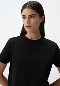 Zwarte katoen t-shirt met een ronde hals, korte mouwen, een gladde textuur en een getailleerd ontwerp. Eenvoudige en minimalistische stijl.