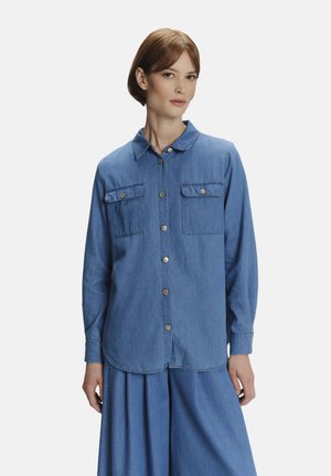 Denim shirt met knoopsluiting aan de voorkant, twee borstzakken, een ronde zoom en lange mouwen. Zachte textuur en middelblauwe kleur.