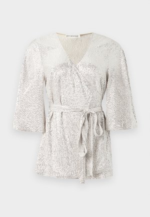 Hõbedase tekstuuriga pluus, millel on V-kaelus, kellukesed varrukad ja vöökohtade sidumiseks rihm. Omab säravat kangast, millel on peened mustri varieerumised.