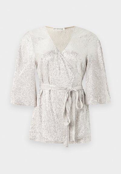 Sivert texturerad topp med V-ringning, klockärm och knytbälte i midjan. Har ett glittrande tyg med subtila mönstervariationer.