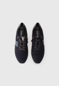 Sneakers in camoscio blu navy con un pannello texturizzato, chiusura con zip e lacci a fantasia. Dettagli in pelle nera sul tallone e sul lato.
