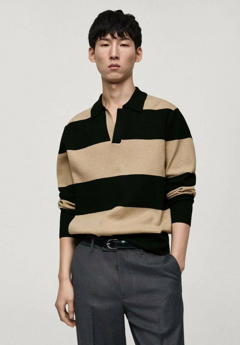 Pulover tricotat cu dungi orizontale negre și bej, guler scurt, croială lejeră, asortat cu pantaloni gri. Textură moale și design casual.