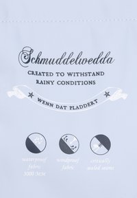 Pilkas audinio etiketė su užrašu "Schmuddelwedda", vandeniui atsparūs ir vėjo nepralaidūs simboliai, taip pat svarbūs siūlių sandarinimo detalės juodai baltame fone.