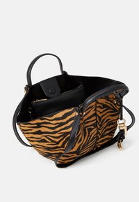 Torba tote w czarno-pomarańczowe paski przypominające tygrysa, z skórzanymi akcentami, o wyraźnym kształcie, z podwójnymi rączkami i zamykaną na zamek kieszenią wewnętrzną.