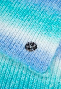 Cappello lavorato a maglia con una sfumatura dal celeste al verde acqua. Include un logo rotondo in argento con un design a stella. Filato morbido e testurizzato.