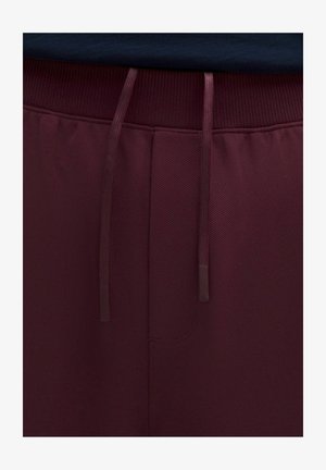 Pantaloni in tessuto bordeaux scuro con trama, coulisse e vita elastica a coste, mostrati in dettaglio ravvicinato.