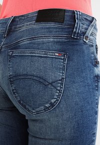 Modré denimové džíny se slim fit, s jemným zesvětlením, černou koženou etiketou v pase a malou logem na zadní kapse.