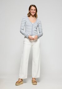 Ljusblå och vitrandig cardigan med V-ringning och knäppning, kombinerad med vita vida byxor och bruna espadrillos.