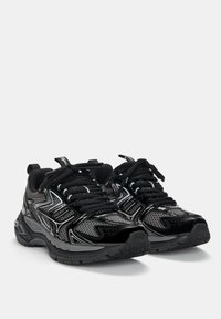Czarne buty sportowe z siateczkową cholewką, błyszczącymi akcentami i teksturowaną gumową podeszwą; zawierają miękkie sznurowadła i wyściełany kołnierz dla wygody.