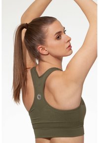 Reggiseno sportivo verde oliva con design racerback, dotato di tessuto testurizzato e dettagli del logo sul retro. Materiale liscio con fascia elastica.