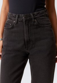 Hoge taille zwarte denim jeans met een rechtbenige pasvorm, voorzien van vijf zakken, een knoopsluiting en subtiele vervaging voor textuur.