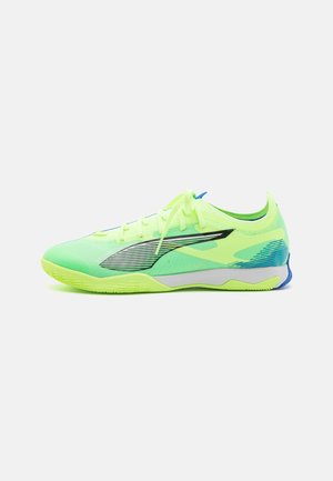 Neon groene sport schoen met een gestructureerd oppervlak, zwarte accenten en een blauwe hiel. Heeft een flexibele zool en vetersluiting.