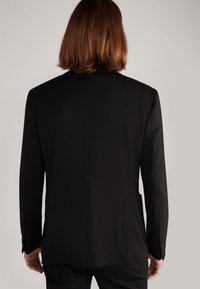 Schwarze maßgeschneiderte Sakkojacke mit glatter Textur, klassischen Revers, einem mittigen Rückenschlitz und geknöpften Manschetten, von hinten betrachtet.