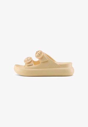 Sandalia beige sin cordones con suela gruesa y dos tiras anchas ajustables con hebillas redondas.