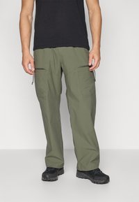 Green cargo pants made of lightweight fabric, featuring zippered pockets, a relaxed fit, and a straight leg design. Worn with black shoes.