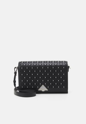 Sac bandoulière noir avec des découpes géométriques, de petites clous argentés, une sangle réglable et une boucle triangulaire argentée sur le rabat avant.