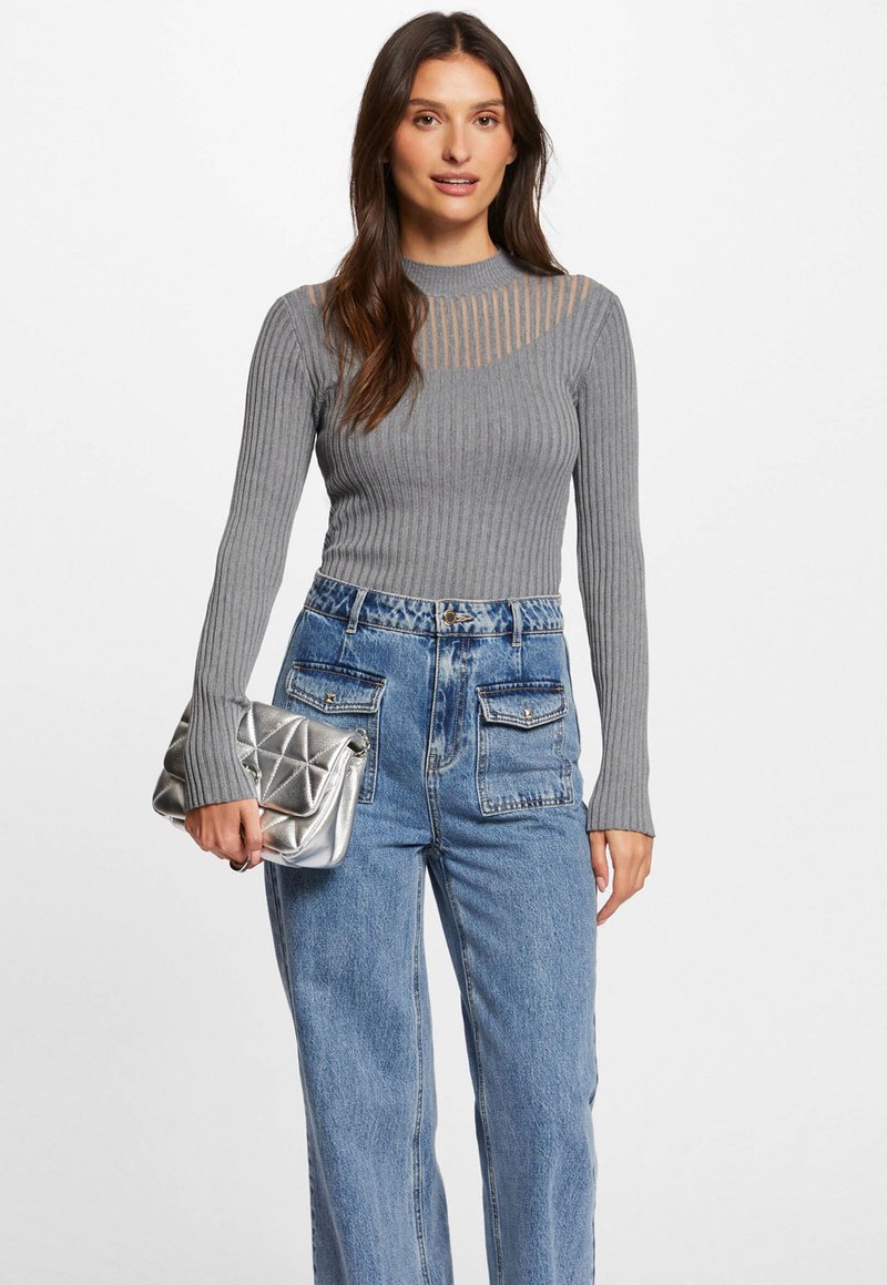 Graues, geripptes Langarmshirt mit horizontalen Netz-Ausschnitten am Ausschnitt, kombiniert mit hoch taillierten hellblauen Jeans und einer silbernen, gesteppten Handtasche.