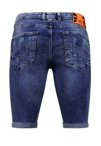 Donkerblauwe denim shorts met een vervaagde textuur. Heeft opgerolde mouwen, twee achterzakken en een oranje label op de tailleband.