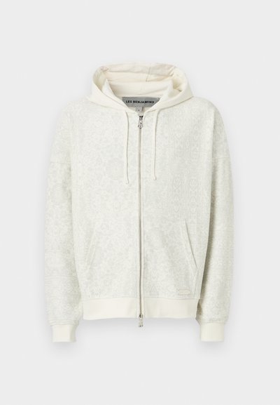 Haut de sweat à capuche zippé gris clair avec un motif discret, capuche à cordon de serrage et poches kangourou. Comprend des poignets et un ourlet côtelés. Texture douce.