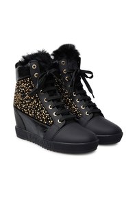 Sneakers neri a zeppa con borchie dorate, lacci frontali e bordo in pelliccia nera attorno alla caviglia, presentati in un paio su sfondo bianco.