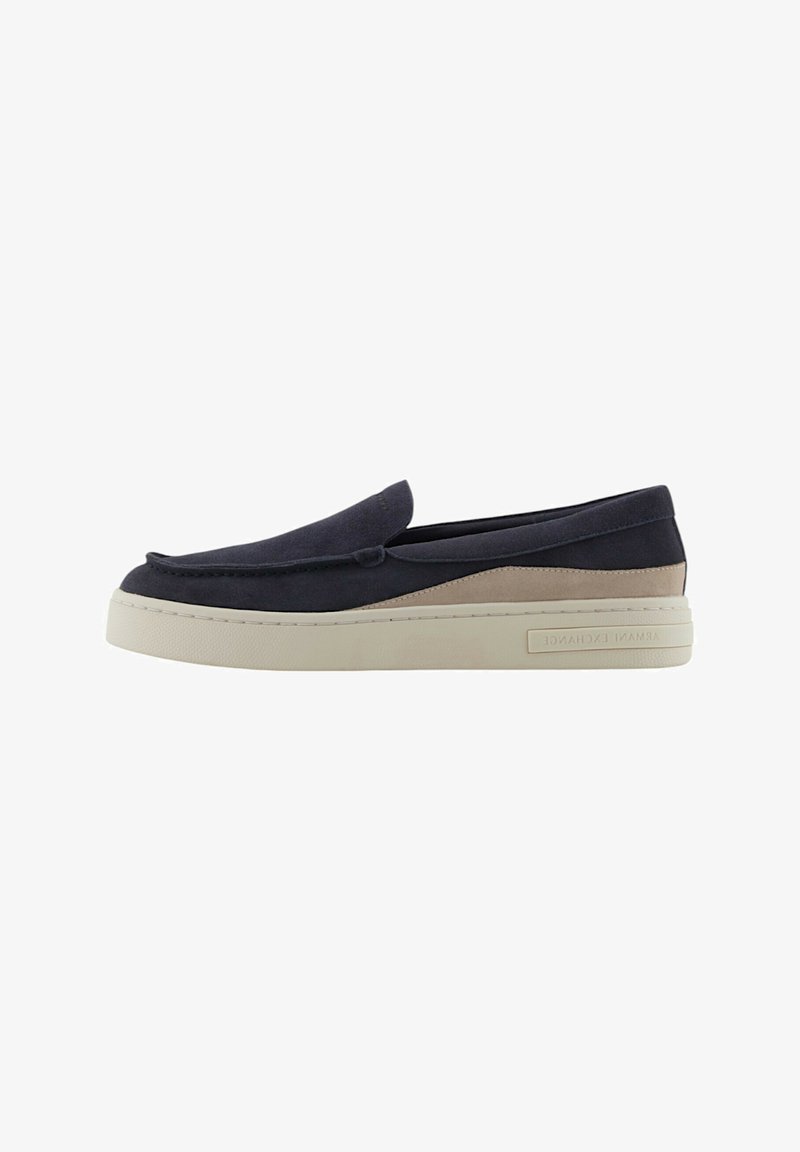 Scarpa slip-on blu navy e beige con una parte superiore liscia simile al camoscio, punta rotonda e una suola in gomma chiara chunky con dettagli di branding.
