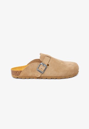Beiger Wildleder-Slipper mit verstellbarer silberner Schnalle, konturiertem Korkfußbett und strukturierter Gummisohle.