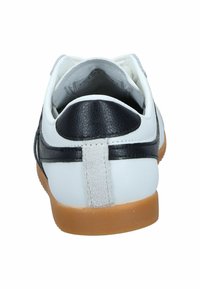 Zapatilla blanca con acentos de cuero negro, que presenta un talón trasero texturizado y una suela de goma. Diseño simple con mínimas decoraciones.