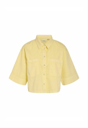 Lyhythihainen, vaaleankeltainen napillinen paita, jossa kaulus ja kaksi etutaskua rintamuksella, lyhyt malli ja keskellä painonapit.