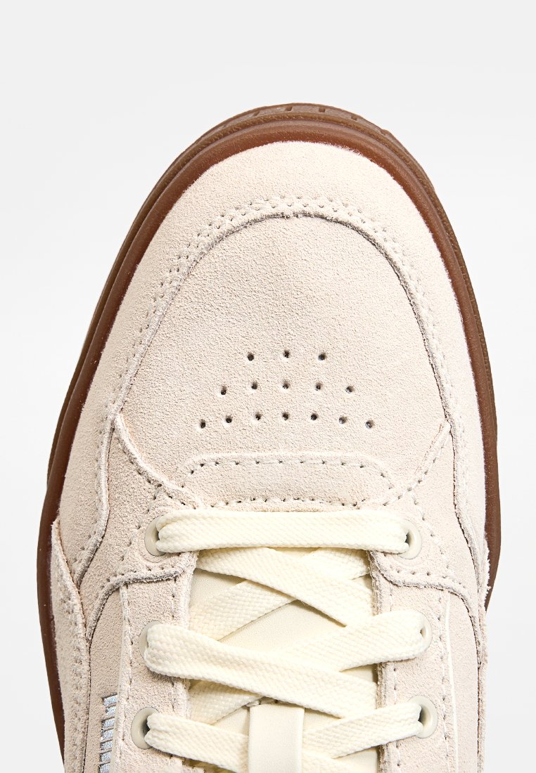 Sneaker in suede beige con punta rotonda, chiusura con lacci color crema, dettagli perforati sulla punta e suola in gomma marrone.