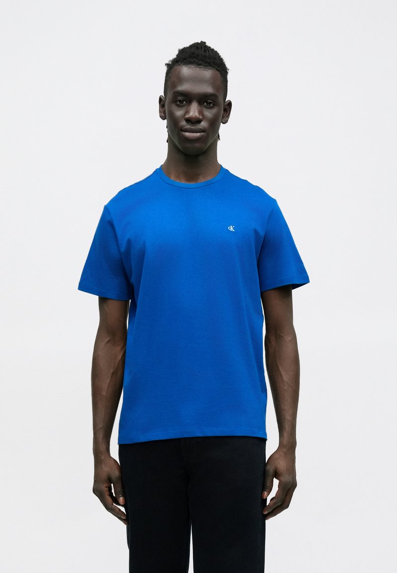 Koszulka w kolorze królewskiego niebieskiego wykonana z bawełny, z okrągłym dekoltem i krótkimi rękawami. Subtelne logo na wysokości klatki piersiowej.