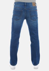 Vaqueros de un azul oscuro con corte recto, cinco bolsillos y una etiqueta de cuero en la cinturilla. Incluye costuras decorativas en los bolsillos traseros.