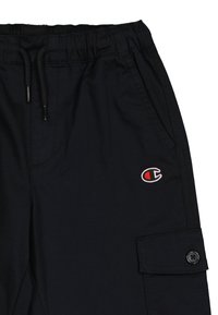 Schwarze Cargo-Hosen mit elastischem Bund, Kordelzug, Seitentaschen und einem kleinen gestickten Logo. Das Material wirkt glatt.